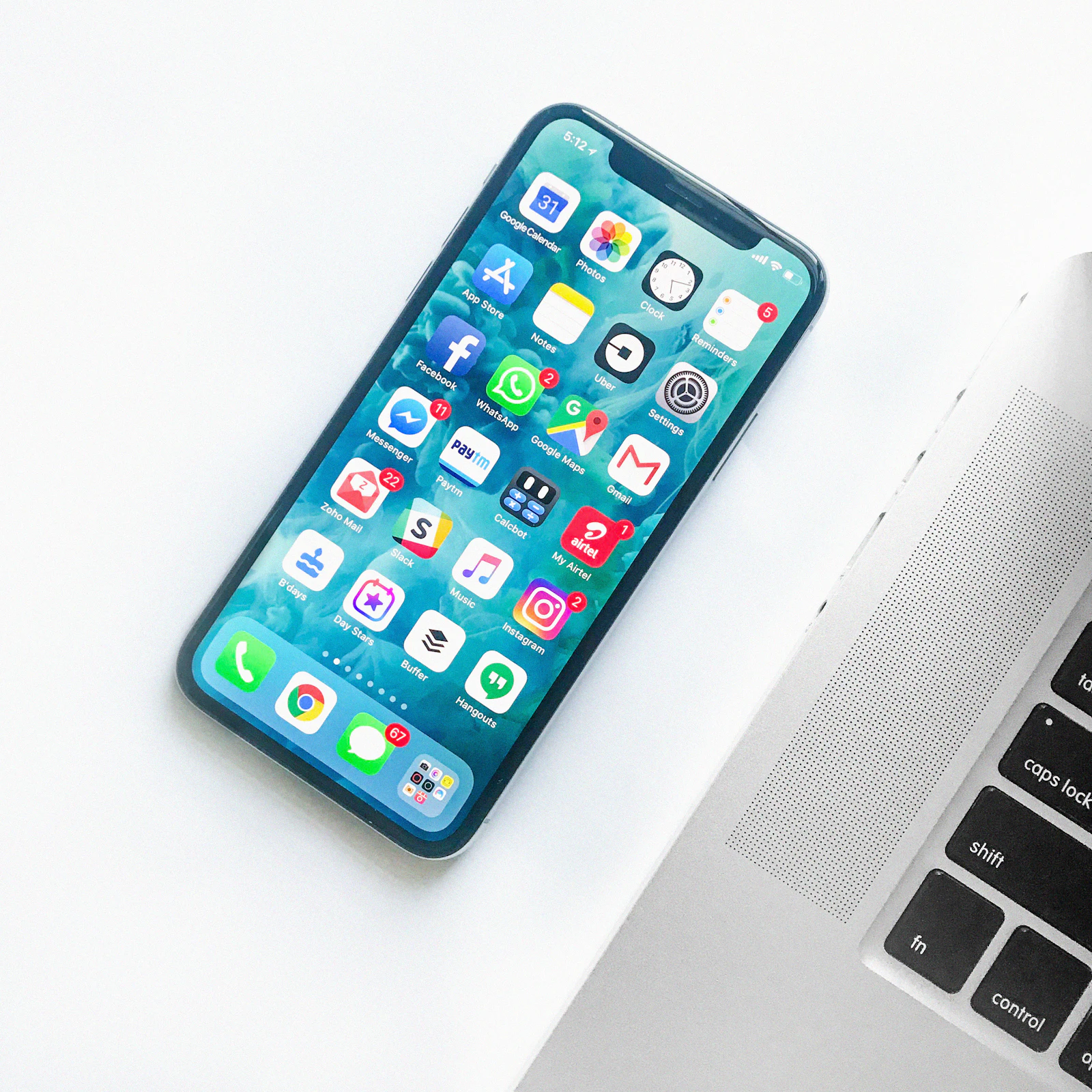 Dizüstü bilgisayar klavyesinin yanında renkli bir uygulama ekranı açık akıllı telefon